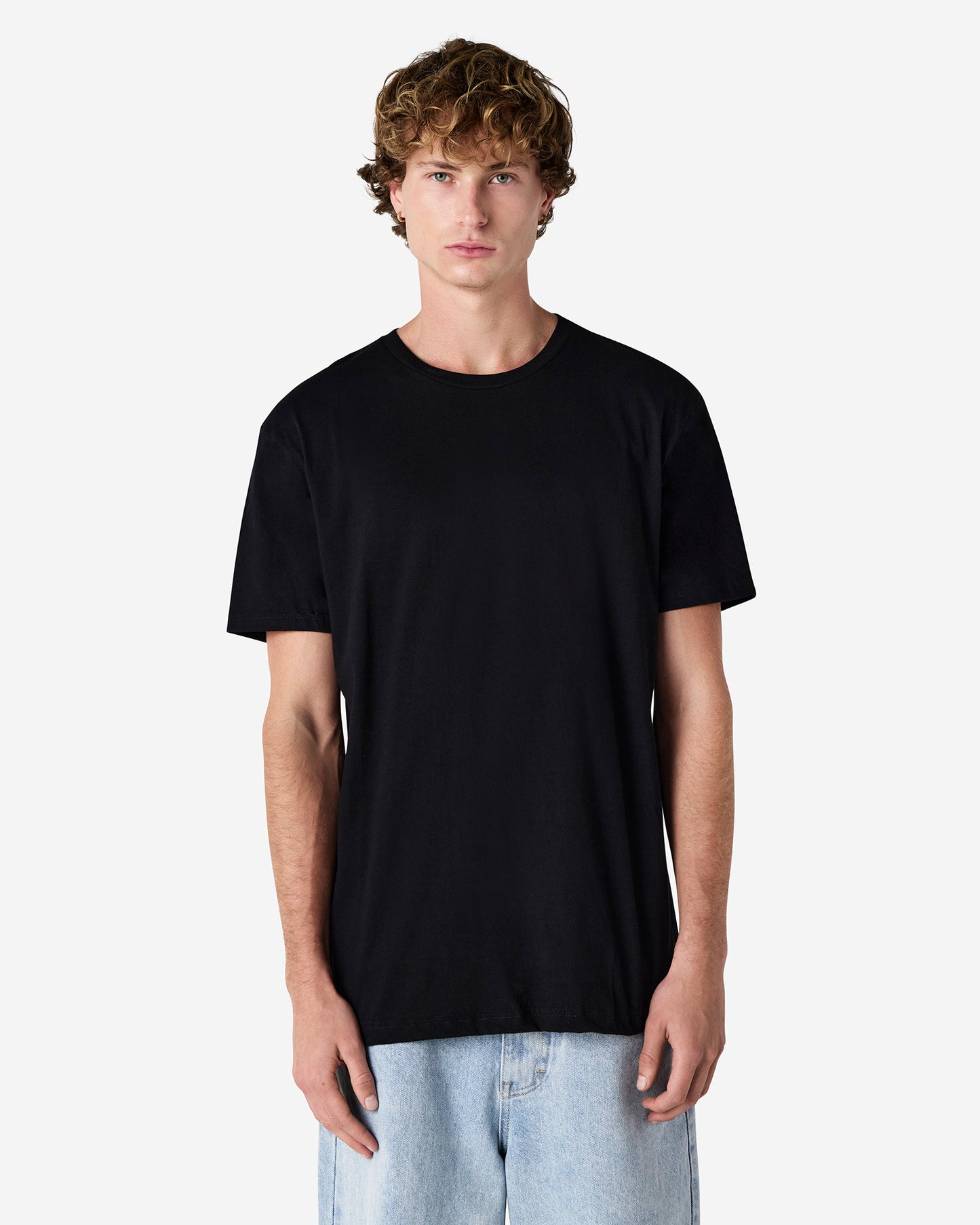 Front view of male model wearing black American Apparel 2001CVC Unisex T-Shirt, styled with relaxed denim jeans for everyday wear-black