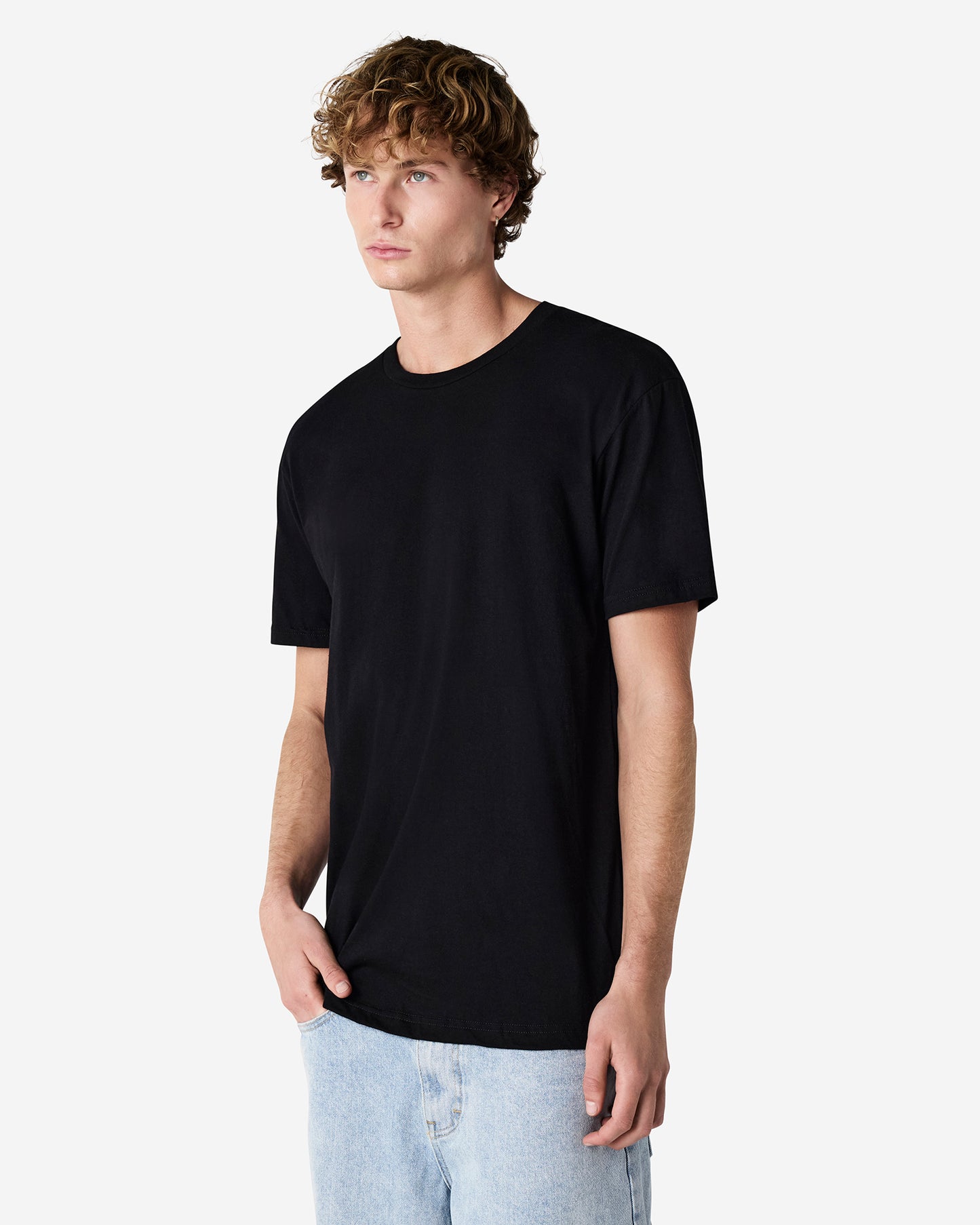 Side angle of male model in black American Apparel 2001CVC T-Shirt, showcasing minimal design and modern silhouette-black