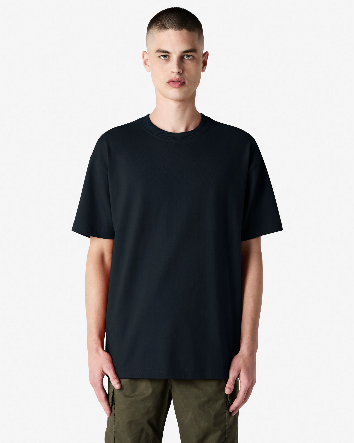 Front view of male model in black American Apparel 9001 Super Heavyweight Oversized Tee, styled with olive pants for a clean minimal look-black