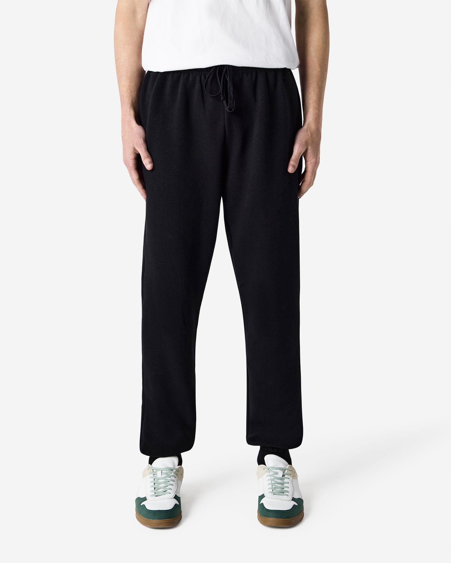Front view of male model wearing black American Apparel RF491 sweatpants paired with white T-shirt and sneakers-black