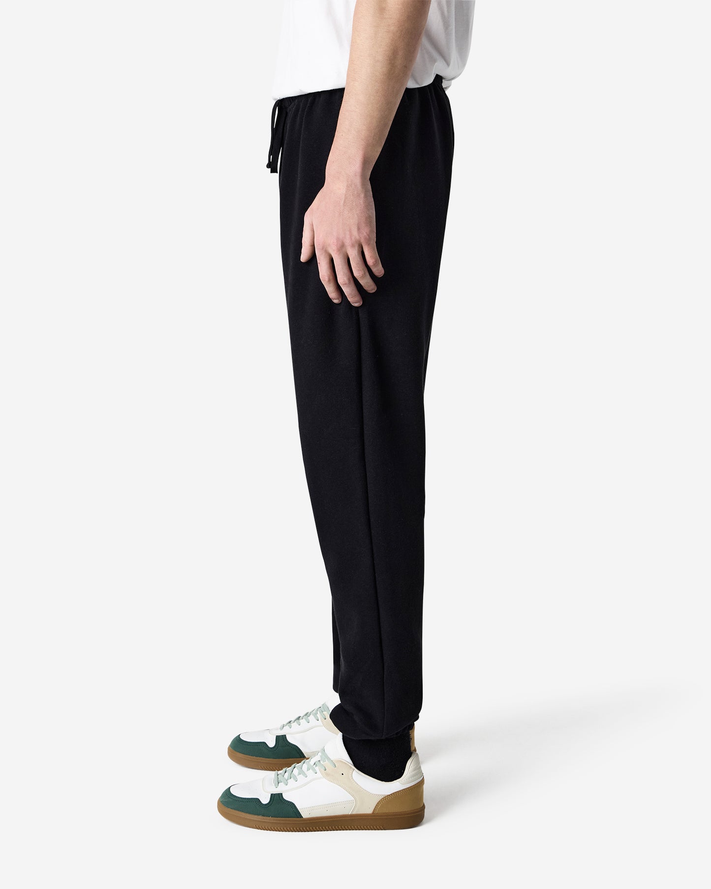 Side view of male model wearing black American Apparel RF491 sweatpants with green and white sneakers-black